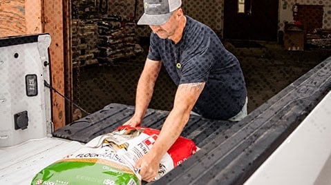 man putting feed bag in truck