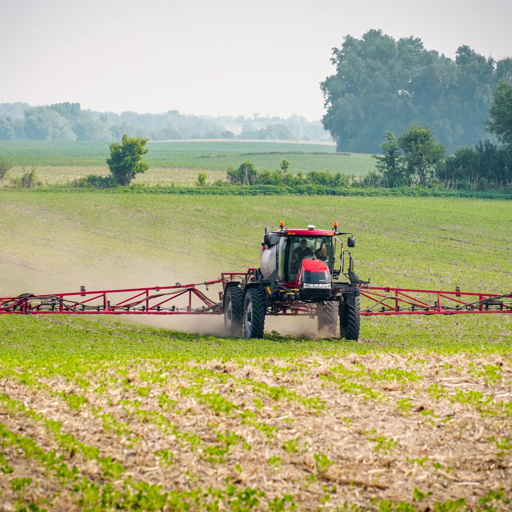 red farmward tractor spraying field