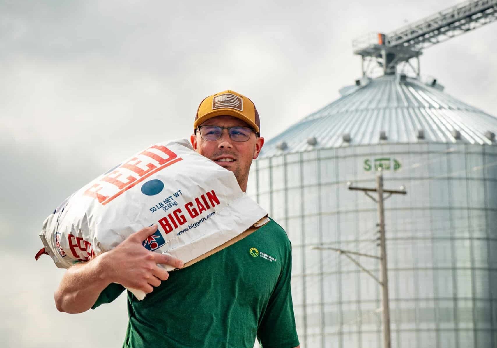 team member carrying feed bag on shoulder